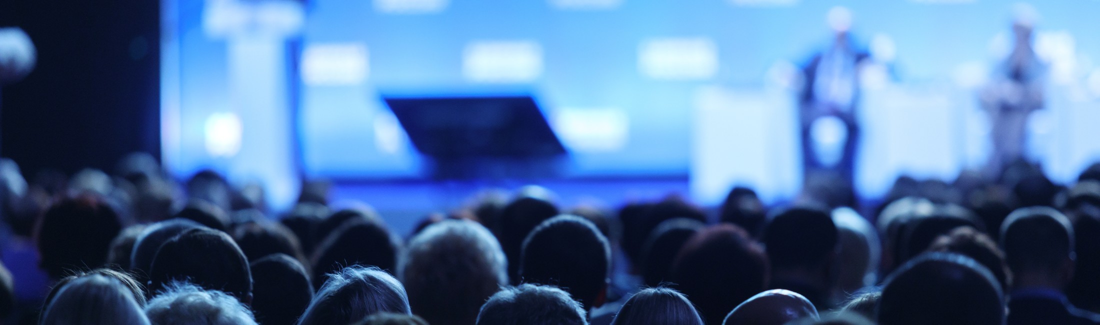 speakers on a stage speaking to an audience